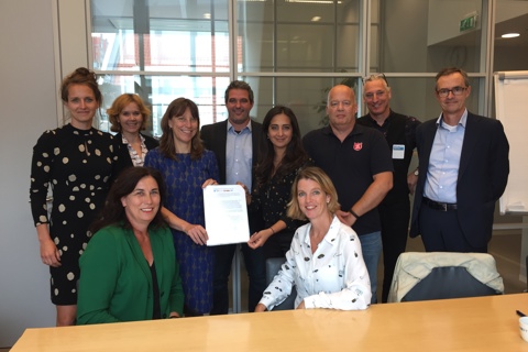 Tien mensen tonen de ondertekening van weer thuis Zaanstad.