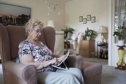 Oudere mevrouw klikt op haar ipad. 