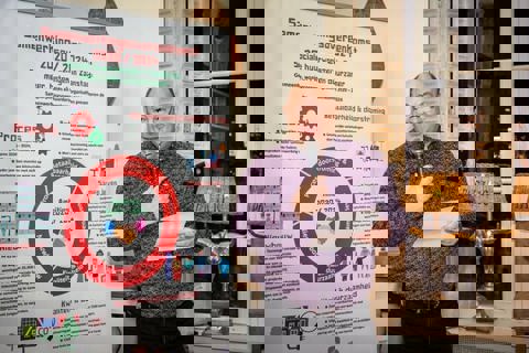 Meneer met microfoon spreekt over samenwerkingsovereenkomst. 