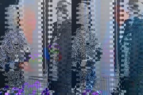 Twee vrouwen hebben viooltjes vast. 