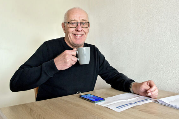 Man lacht met bakje koffie in zijn hand. 