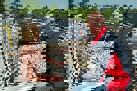 Twee mensen kijken naar een dak met zonnepanelen erop.