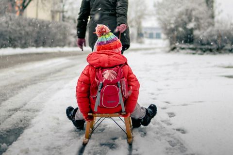 Foto van kind op slee getrokken door vader