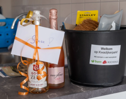 Twee flessen champagne en een welkomstpakket in emmer op het aanrecht