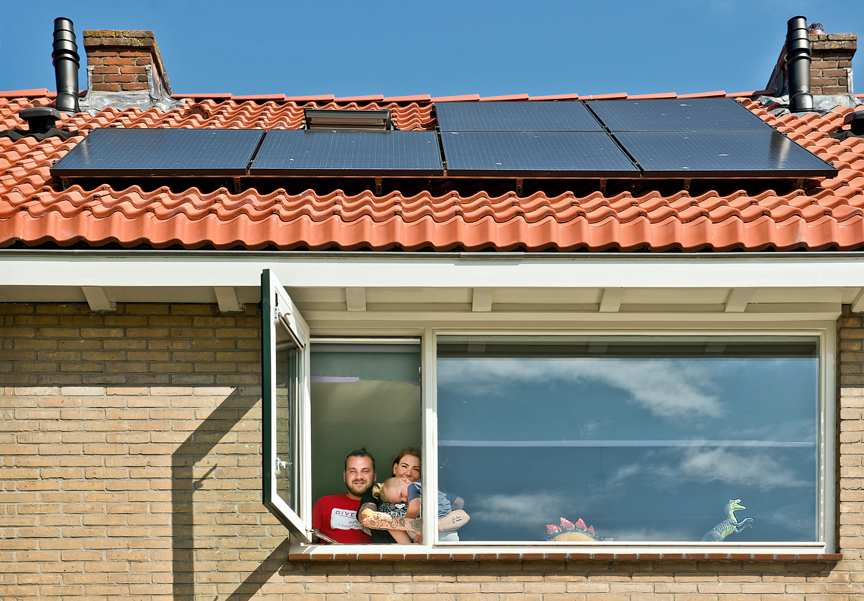 Bewoners showen hun zonnepanelen vanuit het raam.