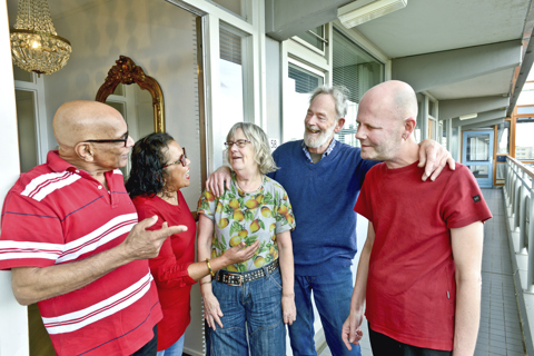 Groep bewoners staan op de galerij, lachend met elkaar in gesprek