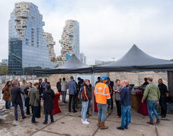 Mensen verzamelen zich onder zwarte tenten op een bouwplaats