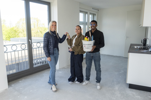 En verhuurmakelaar overhandigt de sleutel aan twee huurders